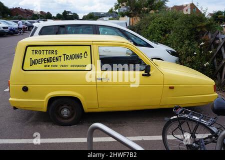 Yellow Reliant Robin 3 wheeler van in a parking lot with Trotter`s Independent trading on the side in Sheringham Norfolk Stock Photo